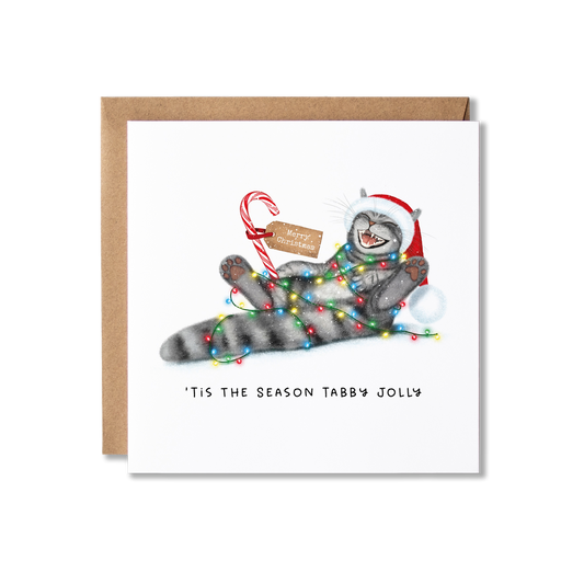 Christmas card with illustration of a tabby cat lying down with its legs in the air laughing, wearing a Santa hat and hold a red and white candy cane with a Merry Christmas tag on with the message Tis The Season Tabby Jolly.
