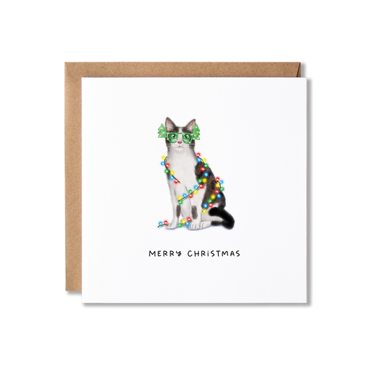 Christmas card with illustration of a grey and white cat wrapped in Christmas lights with the message Merry Christmas underneath.