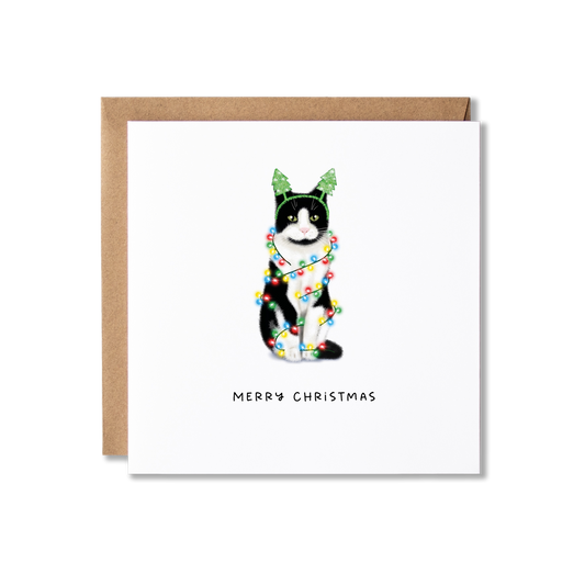Christmas card with illustration of a black and white cat wrapped in Christmas lights with the message Merry Christmas underneath.