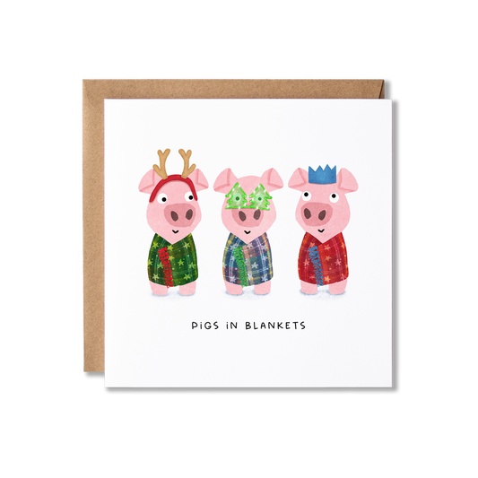 Christmas card with illustration of three little pigs wrapped in different colour blankets and different, as well as one wearing antlers, one wearing green Christmas shape glasses and the other wearing a red party hat crown, with the message Pigs in Blankets.
