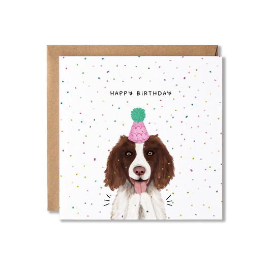 Birthday card with illustration of a Spaniel dog in a pink party hat with a green bobble on top, clapping with confetti in the background and the message Happy Birthday.