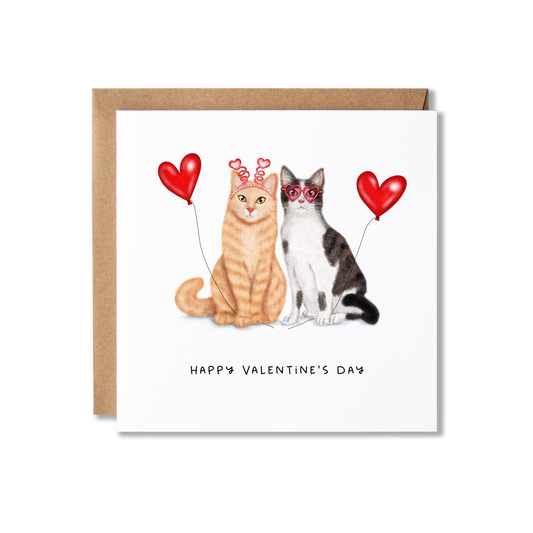 Couple of cats sitting with red heart shaped balloons with the words Happy Valentine's Day underneath.