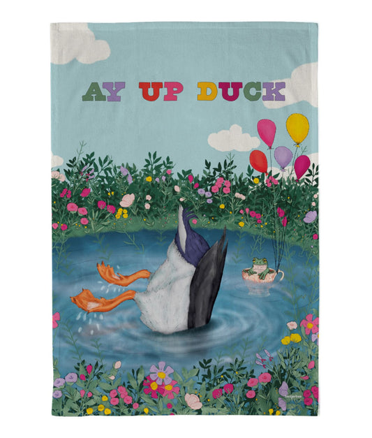 Tea towel with a upside-down duck illustration in a pond and a frog sat in a tea cup held up by colourful balloons with the text 'Ay Up Duck' on a blue background