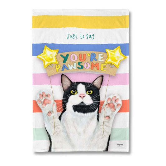 A rectangular printed tea towel featuring a black-and-white cat with raised paws against pastel horizontal stripes, with the phrase 'just to say YOU'RE PAWSOME' and yellow star graphics. The product is photographed alone on a plain white background.