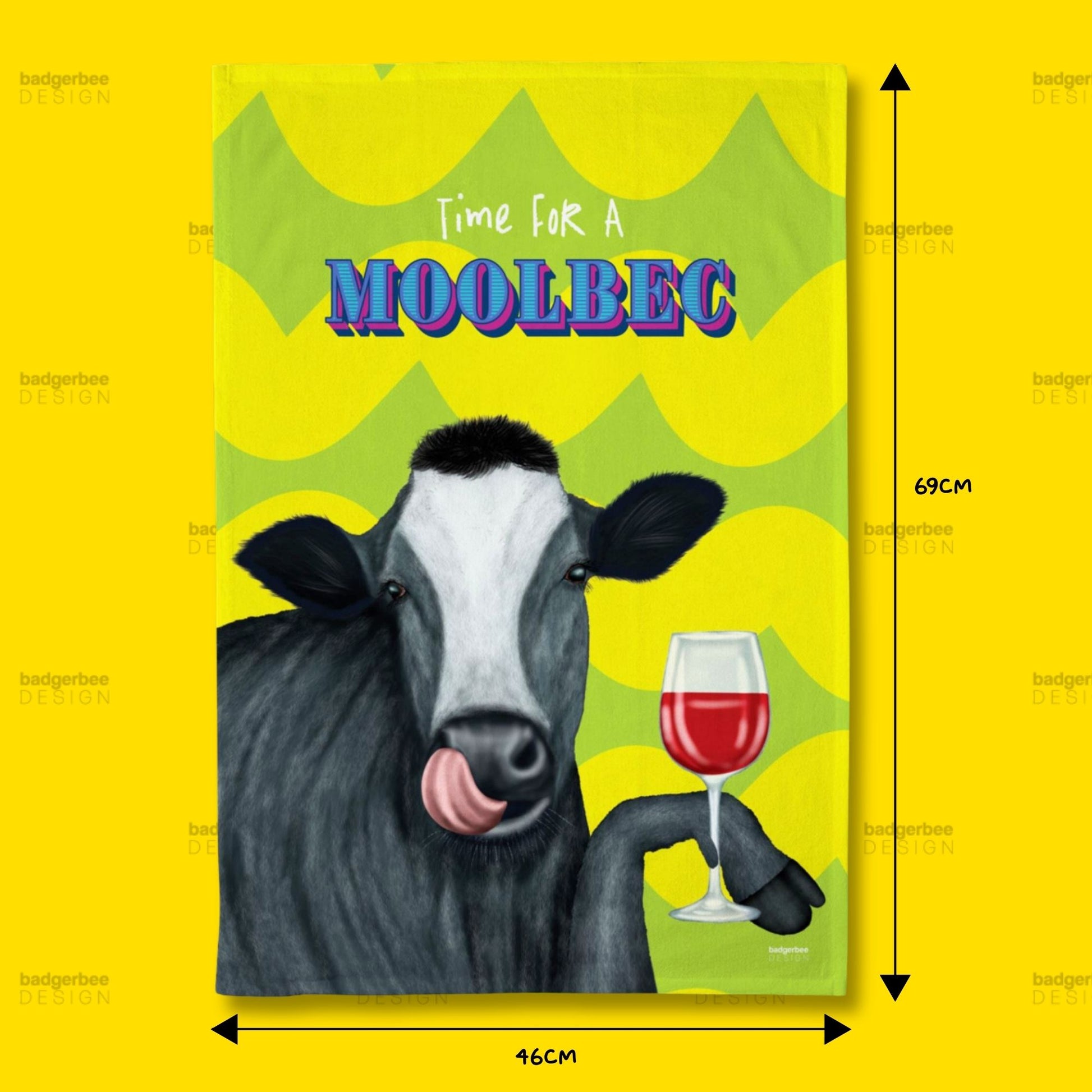 A rectangular printed tea towel featuring an illustration of a cow holding a glass of red wine, with the text 'Time FOR A MOOLBEC' on a bright yellow background. Black dimension arrows and labels indicate 69 cm height and 46 cm width.