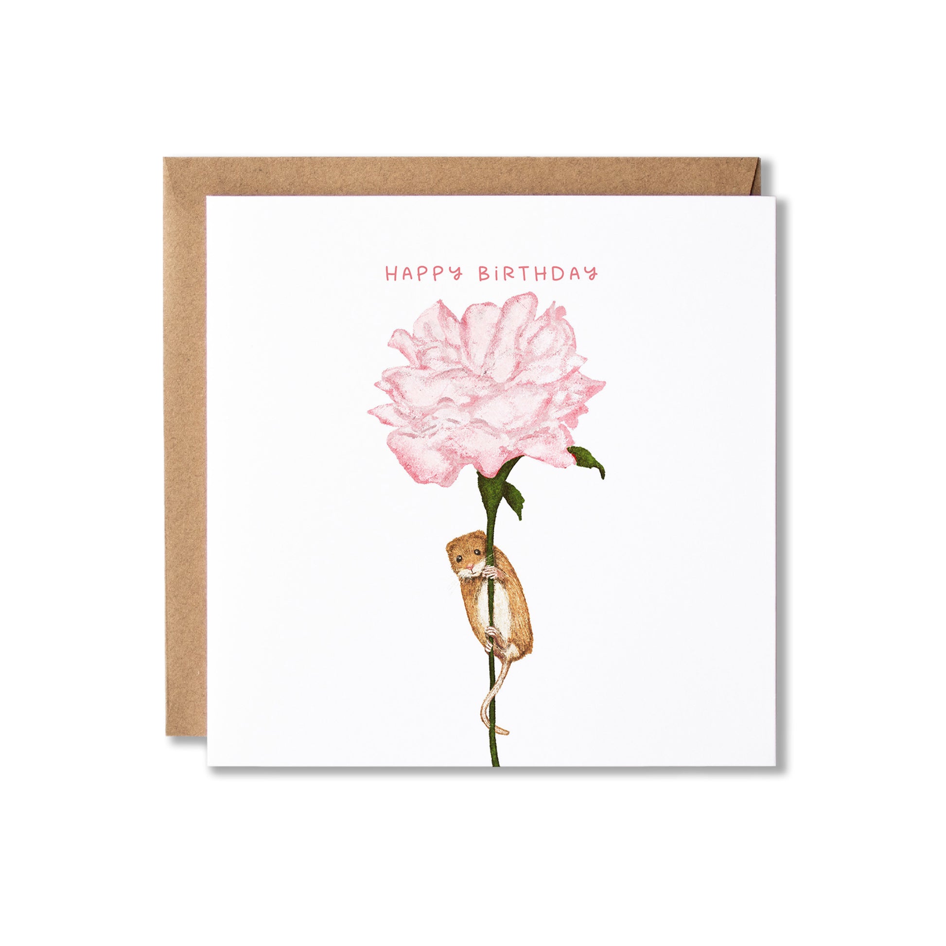 A square white birthday card with a kraft brown envelope behind it, featuring an illustration of a pink flower with a small brown mouse hanging from the stem and the words 'HAPPY BIRTHDAY' in pink at the top.