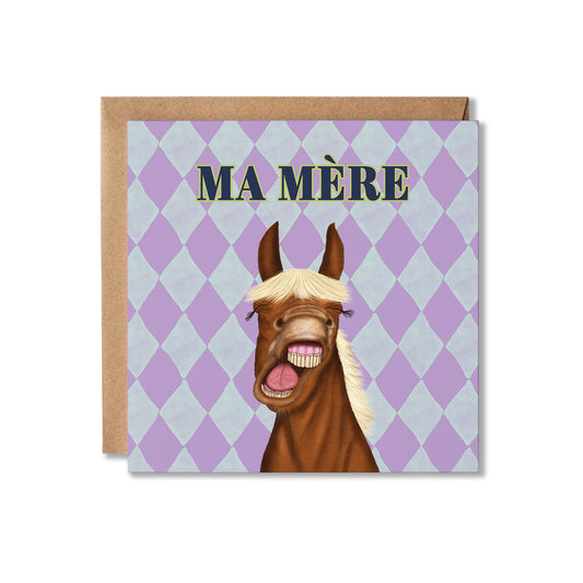 A square greeting card with a brown envelope behind it, featuring an illustration of a smiling horse face with the text 'MA MÈRE' on a lavender and light blue diamond patterned background.