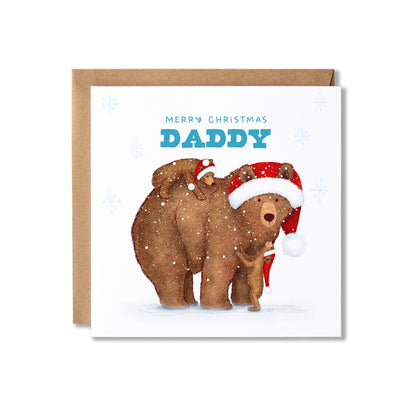 A square Christmas greeting card with a kraft envelope behind it. The card features an illustration of a large brown bear and two smaller brown bear cubs wearing Santa hats, with the text 'MERRY CHRISTMAS DADDY' in blue on a white background.