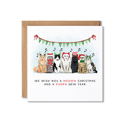 A square white greeting card with a brown kraft envelope behind it, featuring an illustration of six cats and a dog wearing Christmas hats under a green bunting garland. The text at the bottom reads, 'WE WISH YOU A MEOW'S CHRISTMAS AND A PURRY NEW YEAR'.