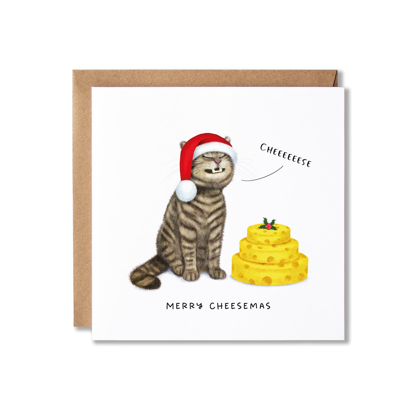 A square greeting card with a brown kraft envelope behind it, featuring an illustration of a tabby cat wearing a red Santa hat next to a yellow cheese cake, with the text 'CHEEEEESSE' and 'MERRY CHEESEMAS'.