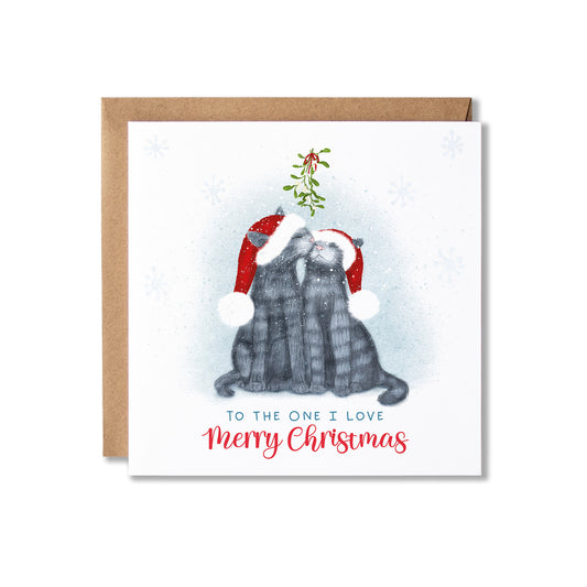 A square Christmas greeting card with a kraft envelope behind it. The card features an illustration of two gray cats wearing red Santa hats and kissing, with mistletoe between them and the text 'TO THE ONE I LOVE Merry Christmas' below.