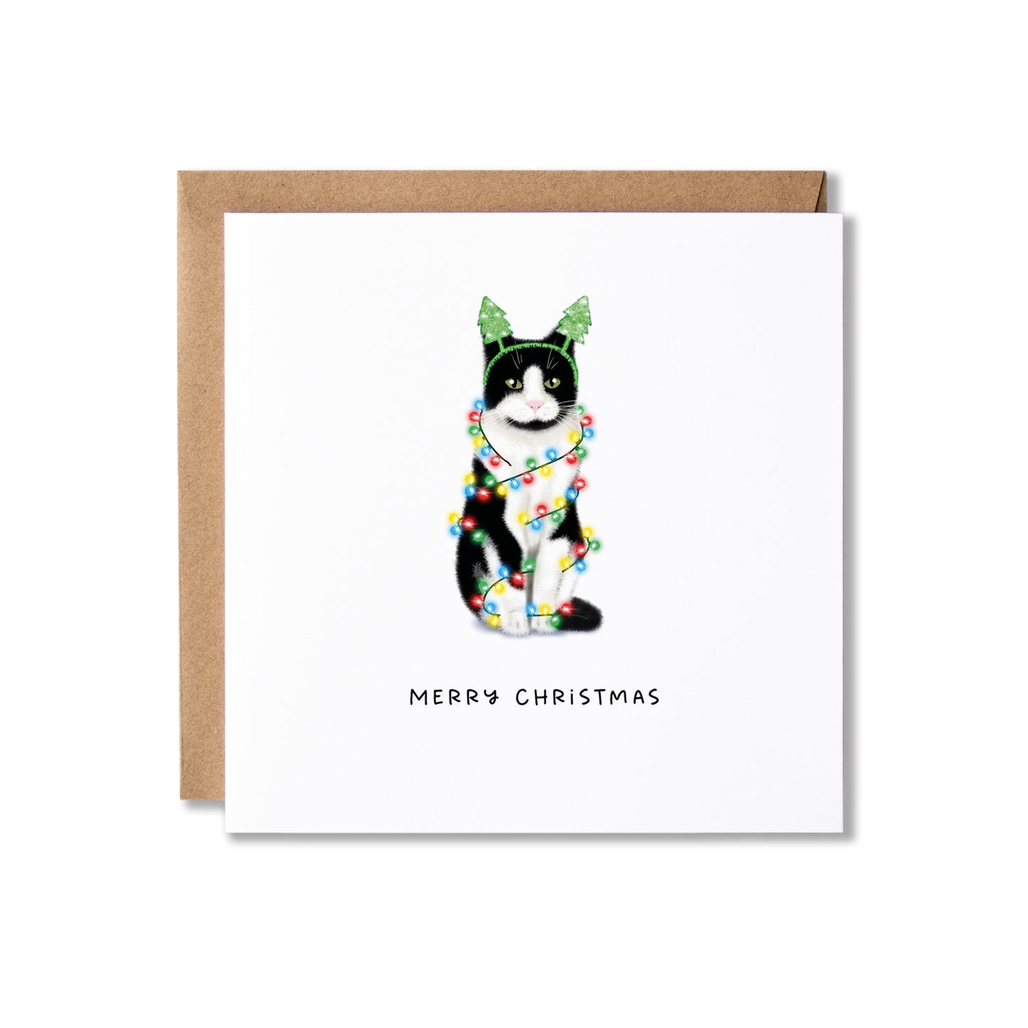 A square white Christmas greeting card with a brown kraft envelope behind it, featuring an illustration of a black-and-white cat wearing green Christmas tree headband and wrapped in multicoloured Christmas lights, with the text 'MERRY CHRISTMAS' below.