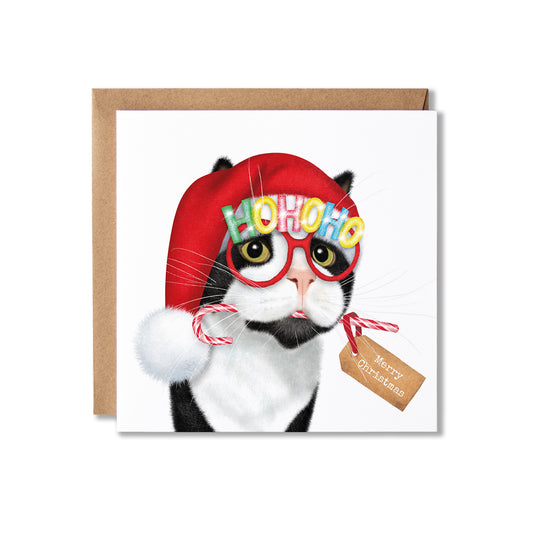 A square Christmas greeting card featuring a black-and-white cat wearing a red Santa hat, red-framed glasses with colorful 'HOHOHO' lettering, and holding candy canes, with a small 'Merry Christmas' tag. The card is shown with a brown kraft envelope behind it on a white background.