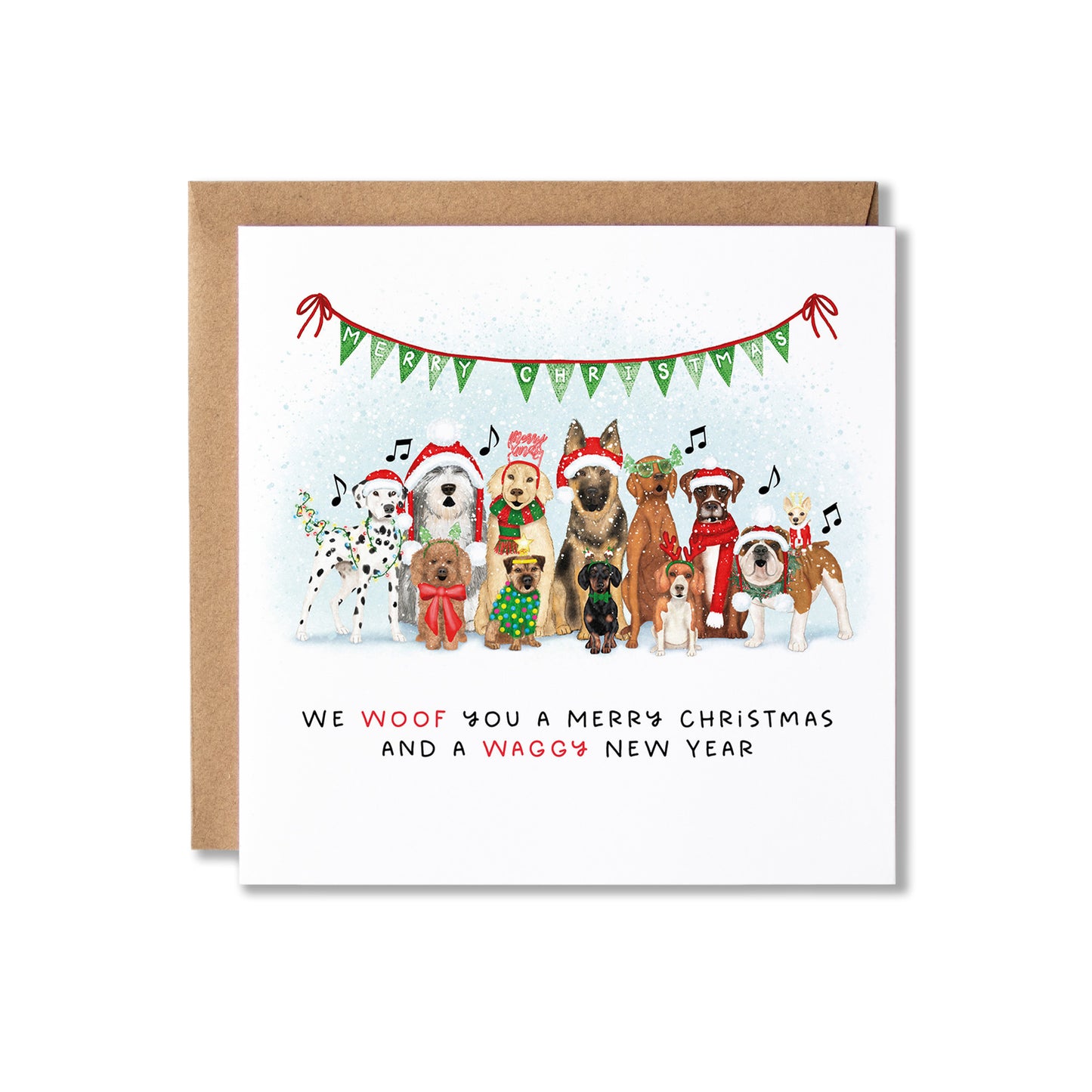 A square Christmas greeting card with a kraft envelope behind it, featuring an illustration of various dog breeds wearing Santa hats and scarves under a green bunting banner. The text at the bottom reads, 'WE WOOF YOU A MERRY CHRISTMAS AND A WAGGY NEW YEAR'.