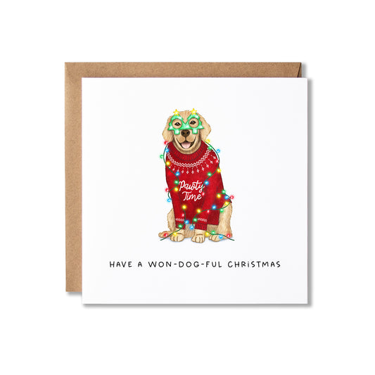 A square white Christmas greeting card with a kraft brown envelope behind it. The card features an illustration of a dog wearing a red Christmas sweater, colorful holiday lights, and a green mask, with the text 'HAVE A WON-DOG-FUL CHRISTMAS' printed below.
