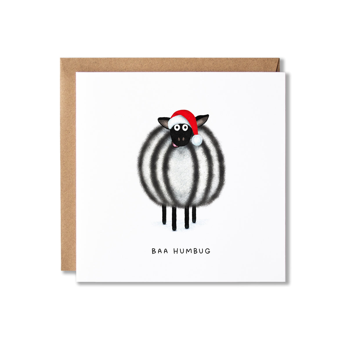 A square white greeting card with a brown kraft envelope behind it, featuring a cartoon sheep with black and white stripes wearing a red Santa hat and the text 'BAA HUMBUG' below.