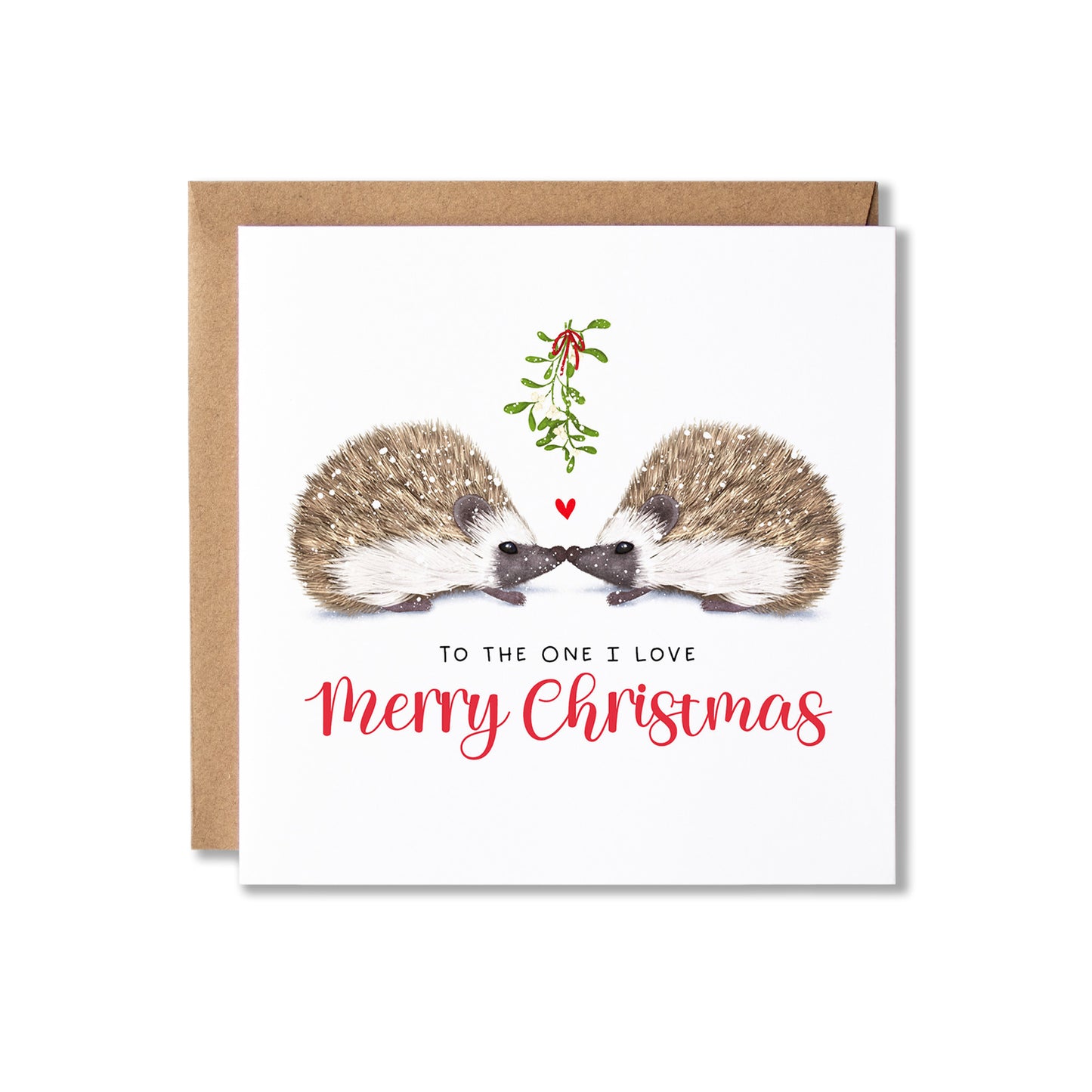 A square Christmas greeting card with a kraft envelope behind it, featuring an illustration of two hedgehogs facing each other under a small mistletoe sprig and red heart, with the text 'TO THE ONE I LOVE Merry Christmas'.