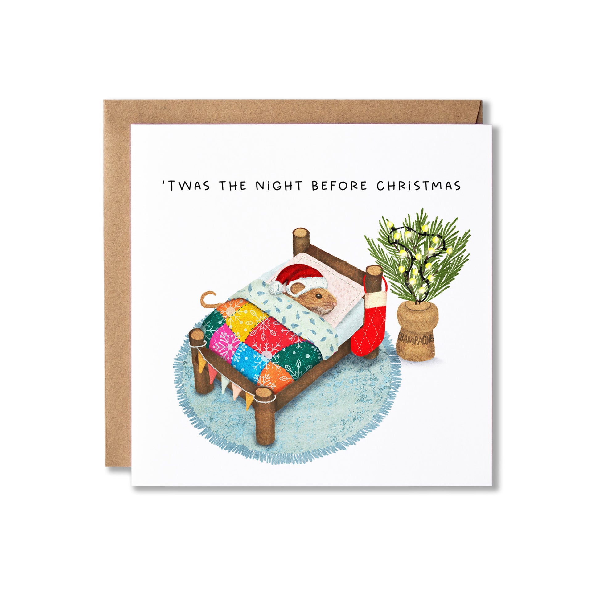 A square Christmas greeting card with a kraft envelope behind it, featuring an illustration of a small mouse wearing a Santa hat in a bed with a colorful quilt, a red stocking, and a potted plant. The card reads, "'Twas the night before Christmas."