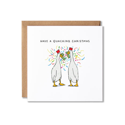 A square white greeting card with a brown kraft envelope behind it, featuring a cartoon illustration of two white ducks red paper crowns, surrounded by colourful confetti, with the text 'HAVE A QUACKING CHRISTMAS' above.