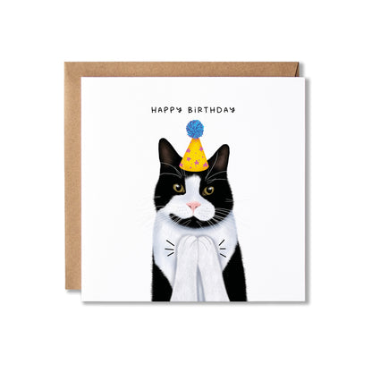 A square birthday card with a white front featuring an illustrated black-and-white cat wearing a yellow party hat, shown with a brown kraft envelope behind it on a white background.