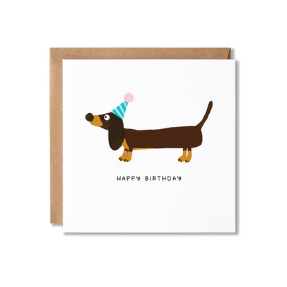A square birthday card with a kraft envelope, featuring an illustration of a dachshund wearing a party hat above the words 'HAPPY BIRTHDAY'.