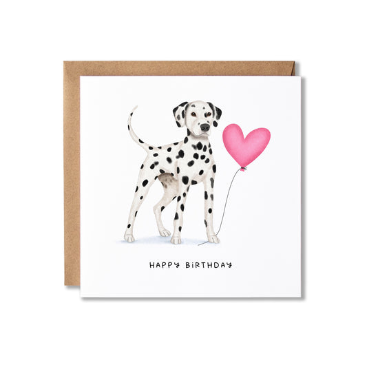 A square birthday card with a brown envelope, featuring a watercolor illustration of a Dalmatian dog holding a pink heart-shaped balloon, with 'HAPPY BIRTHDAY' printed below.