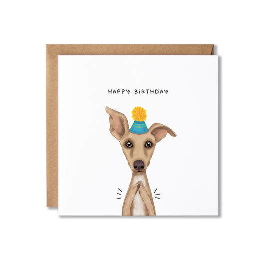 A square birthday card with a brown kraft envelope behind it. The card features an illustration of a light brown dog wearing a blue party hat with a yellow pom-pom, with the text 'HAPPY BIRTHDAY' above it.