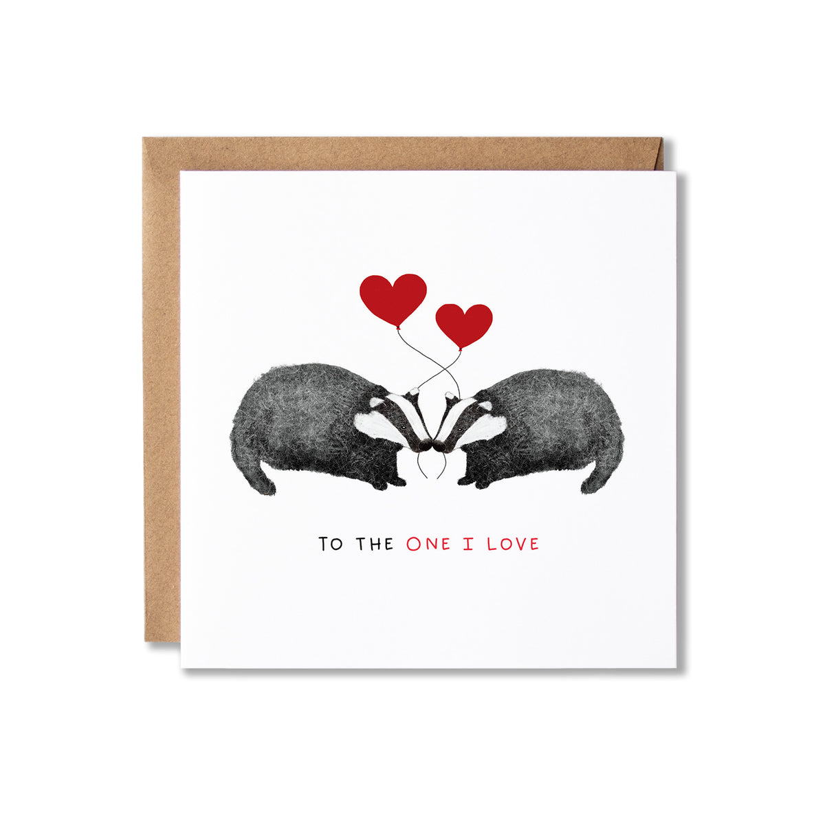 A square white greeting card with a kraft brown envelope behind it, featuring an illustration of two badgers facing each other with two red hearts above them and the text 'TO THE ONE I LOVE' below.