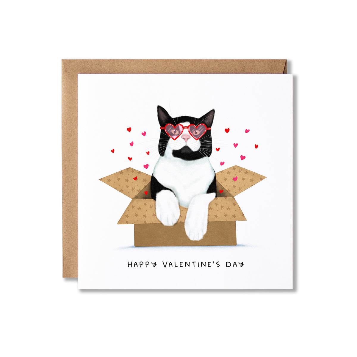 A square Valentine's Day greeting card with a kraft envelope behind it. The card features an illustration of a black-and-white cat wearing red heart-shaped glasses, sitting in an open cardboard box with small red hearts floating around it, and the text 'HAPPY VALENTINE'S DAY' printed below.