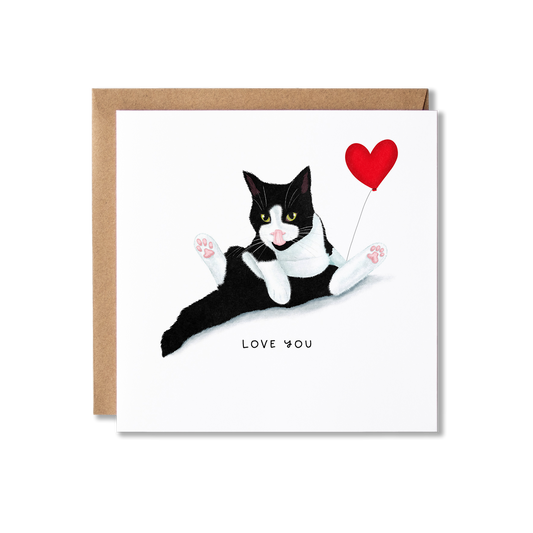 Valentine's Day card with illustration of a black and white cat sat in a funny position having a wash holding a red heart balloon with the message Happy Valentine's Day.