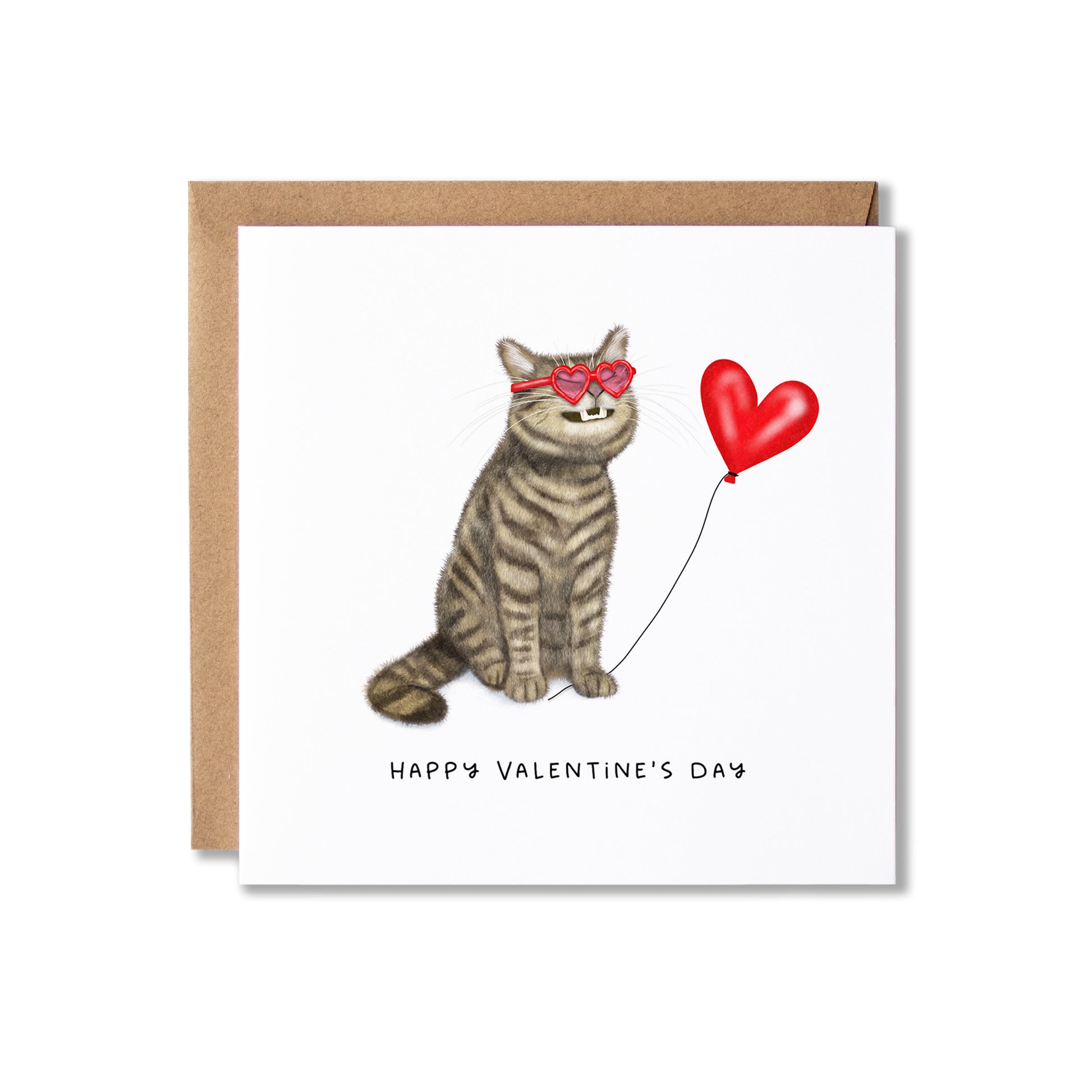 A square Valentine's Day greeting card with a brown kraft envelope behind it. The card features an illustration of a grey tabby cat wearing pink heart-shaped sunglasses and holding a red heart-shaped balloon, with the text 'HAPPY VALENTINE'S DAY' printed below.