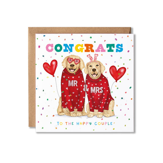 A square congratulations card featuring two illustrated golden retriever dogs in red hearts-patterned sweaters with Mr & Mrs on them, with the text 'CONGRATS' and 'TO THE HAPPY COUPLE'. A kraft paper envelope is placed behind the card on a white background.