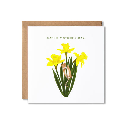 A square Mother's Day greeting card with a kraft envelope behind it. The card is white and features the text 'HAPPY MOTHER'S DAY' above an illustration of yellow daffodils with a small brown mouse climbing among the stems.