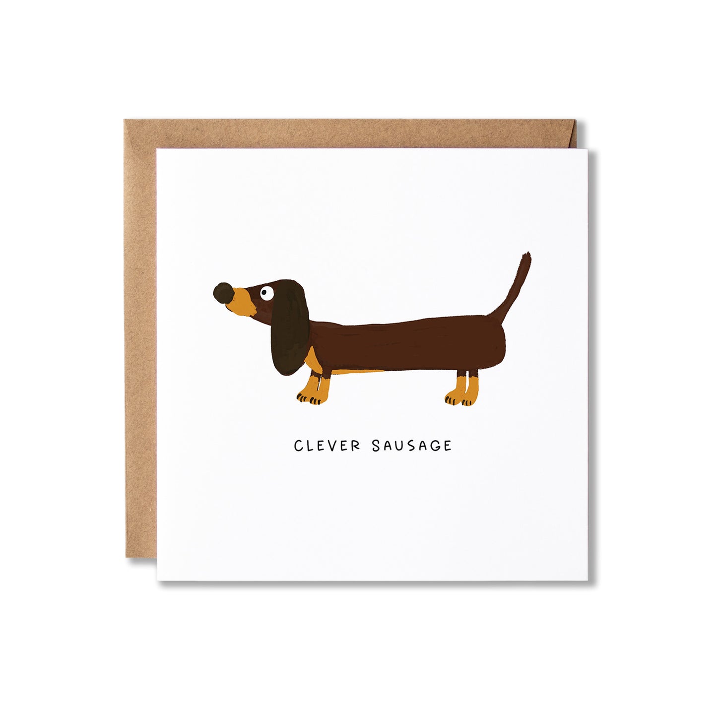 A square white greeting card with a brown dachshund illustration and the text 'CLEVER SAUSAGE' underneath, shown with a brown kraft envelope behind it on a light gray background.
