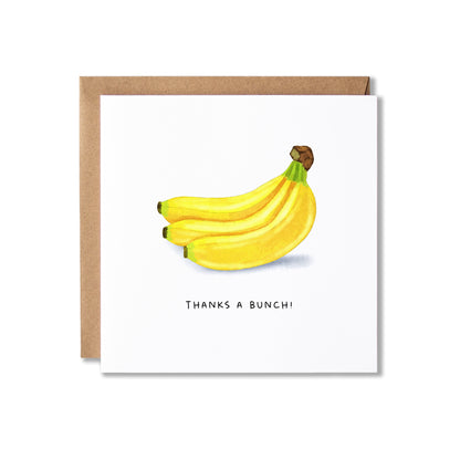 A square white greeting card with a watercolor illustration of three yellow bananas and the printed phrase 'THANKS A BUNCH!' below, shown with a brown kraft envelope behind it on a light gray background.
