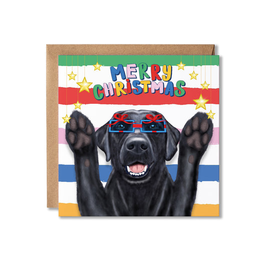 A square Christmas greeting card featuring a black dog wearing present shaped glasses and raising its paws, with the text 'MERRY CHRISTMAS' in colorful letters. The card has a striped background and is shown with a brown kraft envelope.