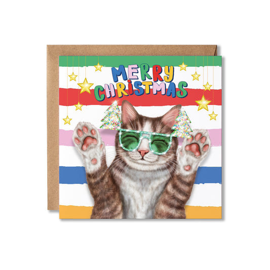A square Christmas greeting card with a brown kraft envelope behind it. The card features a tabby cat wearing green Christmas tree sunglasses, with colourful striped bands and the text “MERRY CHRISTMAS” across the top.