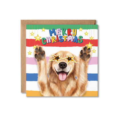 A square Christmas greeting card featuring a golden retriever with paws raised and star-shaped glasses, with the text 'MERRY CHRISTMAS' above. The card has colorful horizontal stripes and is shown with a brown kraft envelope behind it on a white background.