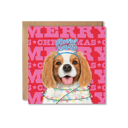 A King Charles Spaniel dog in a Merry Xmas headband and wrapped in Christmas lights with a colourful Merry Christmas background