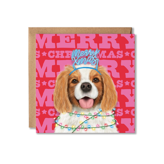 A King Charles Spaniel dog in a Merry Xmas headband and wrapped in Christmas lights with a colourful Merry Christmas background