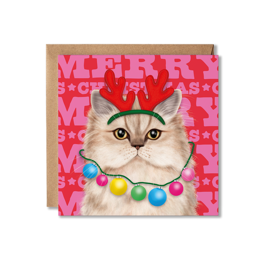 A Persian cat with a red antler headband and bauble necklace with a colourful Merry Christmas background