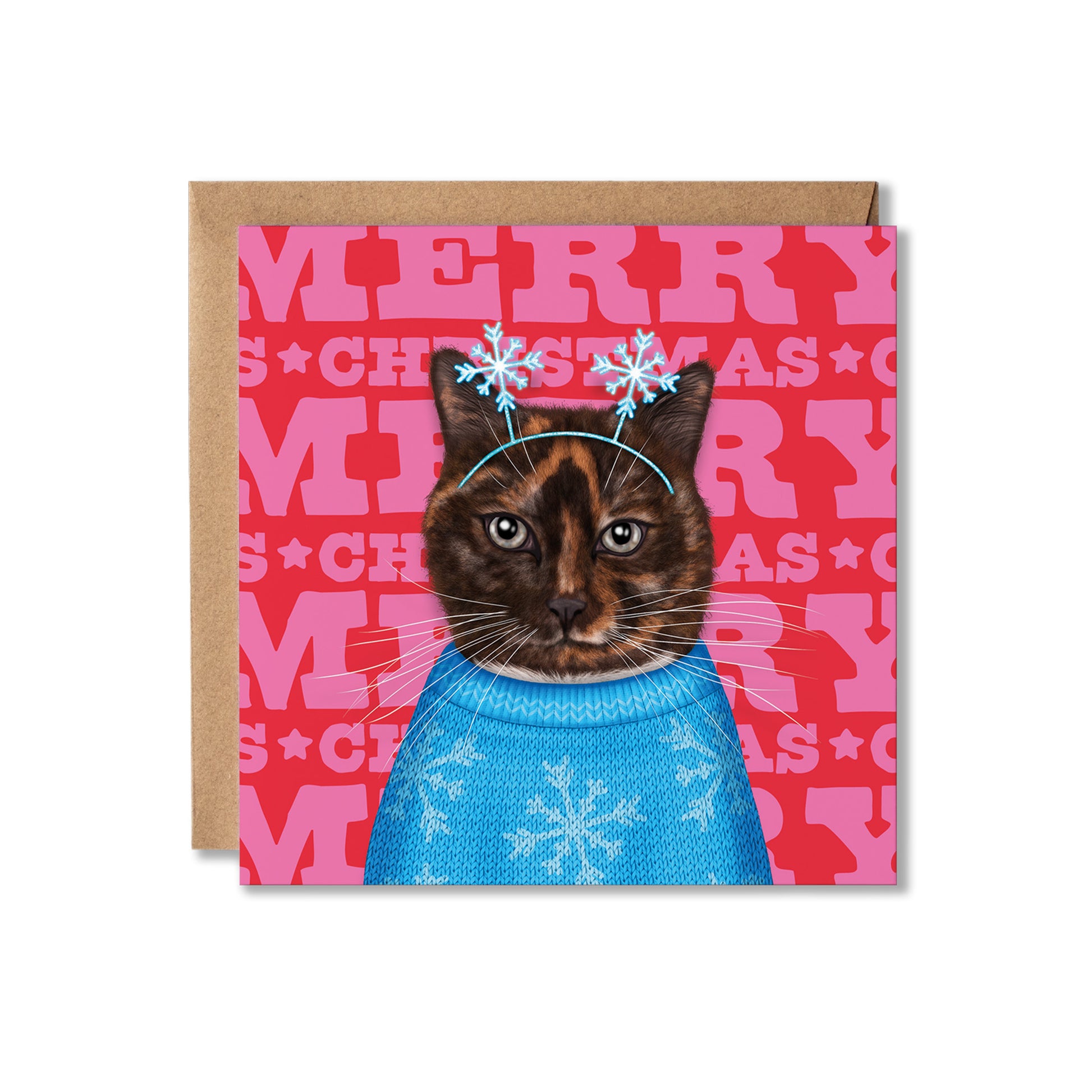 A square Christmas greeting card featuring a cat illustration wearing a blue knit sweater and snowflake headband, with a pink patterned background and brown envelope behind it.
