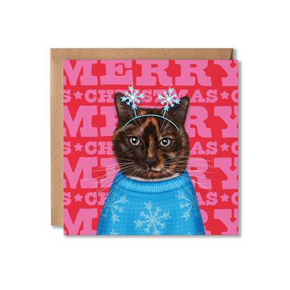A Tortoise shell cat with a blue snowflake knitted jumper and snowflake headband with a colourful Merry Christmas background