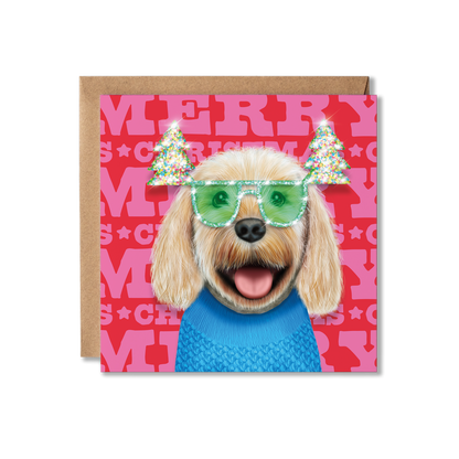 A cream cockerpoo dog in a blue knitted jumper and green Christmas tree glasses with a Merry Christmas background