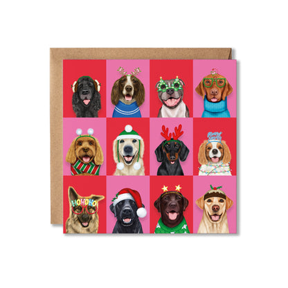 A square greeting card with a brown kraft envelope behind it, featuring a 3x4 grid of illustrated dogs wearing festive holiday accessories on bright pink and red backgrounds.